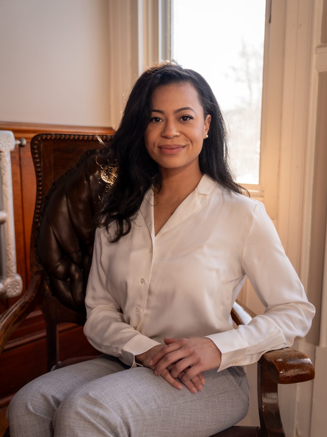 Dr. Alexandra Occean, chiropractor, seated in a leather armchair by a window